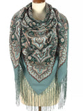 Paisley patterned scarf with fringe on a mannequin against a white background. The green base color combined with teal and black paisley gives this scarf a traditional yet elegant feel. Large enough to wrap comfortably and style in different ways.