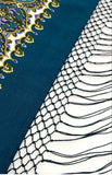 Decorative fringed shawl in teal and yellow pattern with intricate design on a white background