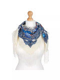 Scarf with blue floral pattern and white fringe on a mannequin against a white background. It expresses calm elegance in milky white with a light blue herbal pattern.