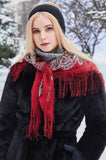 Woman wearing a red scarf and black coat in a snowy landscape