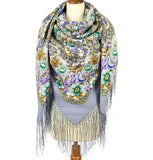 Decorative large scarf with floral patterns and fringe on a mannequin against a white background