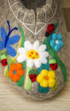 Felted decorative item with flowers, butterflies, and ladybugs on a wooden surface