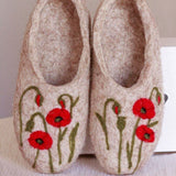 Pair of felted slippers with floral embroidered poppy design next to a white box.