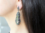Long earring on a woman earlobe made of sterling silver and marcasite. The stone is pale nacreous green stone.