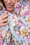 Woman wearing a floral-patterned headscarf with visible branding.
