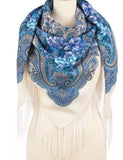 Blue floral lily scarf with fringe on a mannequin against a white background. A square milky white shawl with light blue flowers, simple and timeless, easy to wear.