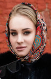 Slavic woman wearing a colorful black and red patterned woolen headscarf with a brick wall background