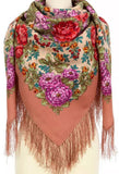 Close-up shot of a manequen wearing a premium merino wool scarf. The square scarf displays a romantic design of red and purple roses on a neutral brown background, highlighted by long fringing at the edges.