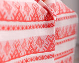 Close-up of a red and white patterned table runner with text overlay reading '56% cotton 44% linen.