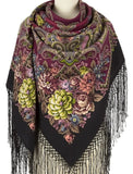 A classy portrait of a manequin elegantly showcasing a traditional woolen shawl. The blanket-style merino wrap serves as both a head covering and a scarf, presenting a vivid contrast between a heavily patterned red paisley upper half and a dark black lower half filled with lush pink, green, and orange rose bouquet ornaments.