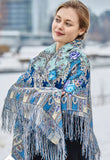 A Slavic blond woman with a large merino wool shawl with silky fringe around her shoulders. The shawl is with large peony flowers.