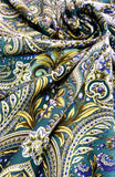 Close-up of intricate paisley pattern shawl with green, gold, and blue colors.