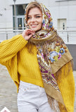 Woman wearing a colorful yellow scarf with field flowers in sky blue and purple. It is made of high quality sheep wool, silky fringe and the shawl is lightweight.