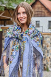 Woman wearing a colorful patterned scarf outdoors with a rustic background