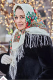 A woman wearing a beautiful Slavic traditional head shawl made of 100% merino wool. The natural sheep wool features a white-red base with a delicate herbal pattern in red, yellow, and green.