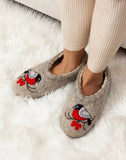 Gray Slavic woolen slippers with bullfinch bird designs worn by a person on a white fluffy surface