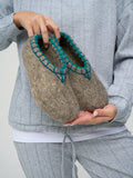 Gray slippers with round toe made from merino wool in a woman`s hands