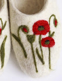 White felted slippers with red floral designs on a white background