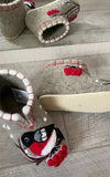 Pair of merino wool slippers with cartoon character design on a wooden floor
