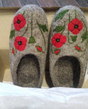 Pair of gray merino wool slippers with red floral designs on a white surface.