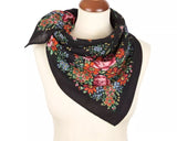 Black merino wool Slavic scarf with colorful floral pattern on a mannequin against a white background