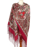 Red paisley patterned scarf with fringes on a mannequin against a white background. The shawl is made of merino wool and silky fringe.