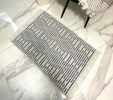 Rectangular doormat with geometric stripped pattern on a tiled floor