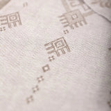 Close-up of a light beige woven textile with a subtle geometric pattern.