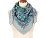 Patterned teal blue scarf on a mannequin with a white background