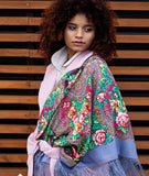 A woman wearing a beautiful ethnic Slavic shawl made of 100% merino wool. The natural sheep wool features blue-gray tones with soft pink floral patterns.