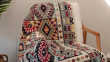 Chair covered with a colorful patterned blanket against a neutral wall.