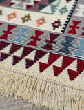 Close-up of a patterned rug with geometric design and fringes.