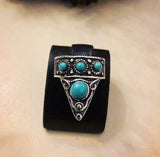 An adjustable sterling silver thumb ring with a triangular shape featuring lab light blue turquoise stones on a black background.