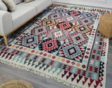 Multicolored  white, blue and red patterned Armenian rug on a wooden floor with a sofa and wicker chair in the background.