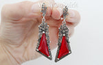 These earrings are a statement piece, pure and simple. The large red stones, a vibrant crimson against the cool sterling silver, immediately draw the eye. Their length adds a dramatic flourish, perfect for those who love to make an entrance. The intricate marcasite detailing lends a touch of old-world glamour, a whisper of medieval style that elevates them beyond the ordinary. The bow detail, while delicate, adds a touch of  femininity amidst the bold design, preventing them from feeling too heavy.