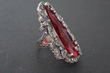 A luxury silver ensemble featuring a dome-shaped ring and long drop earrings with a royal Renaissance vibe. The faceted, clear red stones are perfectly framed by glittering marcasites and detailed openwork filigree. Crafted in premium 925 sterling silver with a beautiful antique finish.