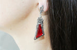 These earrings are not for the faint of heart; they are bold, statement pieces that evoke a sense of old-world romance and majestic elegance. Featuring large, captivating ruby red stones set within intricately detailed sterling silver frames, these earrings are a true head-turner.

