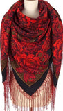 Red floral patterned scarf with fringes on a mannequin. A high-quality merino wool palantine featuring dense red vintage rose bouquets and a contrasting black lace pattern.