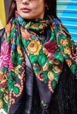 Person wearing a colorful floral vintage Slavic scarf with a black background