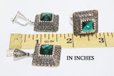 Marcasite earrings and ring with green stones near the yellow ruler in inches.