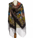 Colorful vintage patterned black scarf with fringes and orange and green peony flowers on a mannequin against a white background.
