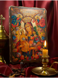 A colorful religious icon plaque of the Virgin Mary holding the infant Jesus, displayed on a stand in a styled setting with a lit candle, a brass oil lamp, and draped burgundy fabric. Vibrant Orthodox Christian icon of the Virgin Mary Unfading Flower with Baby Jesus, featuring a bright, detailed vintage style surrounded by colorful blooming flowers and angels on a wooden panel background.