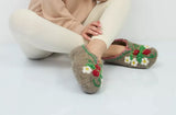 Woolen slippers made of natural wool with strawberry embroidery on woman`s legs