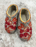 Woolen slippers with red strawberries on a gray floor.