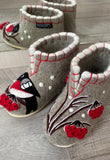Pair of gray slippers with red accents and bird design on a wooden floor.