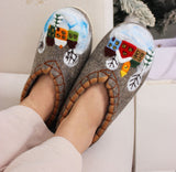 Pair of decorative warm woolen slippers with winter scene design worn by a person.