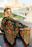 This extra-large scarf features a classic herbal pattern in earthy green and brown shades. Worn wrapped generously around the shoulders, it showcases a vintage, retro aesthetic crafted from natural merino wool with a delicate silky fringe.