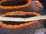 Felted animal-shaped slippers made of fluffy natural wool with orange accents and a ruler for scale on a dark background