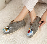 Gray merino wool slippers with snowman design on a light carpet