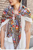 This oversized white scarf is wrapped gracefully around the shoulders, displaying a retro Slavic herbal pattern in bold red and yellow. Made from natural merino wool and finished with a silky fringe, it embodies tradition and elegance.